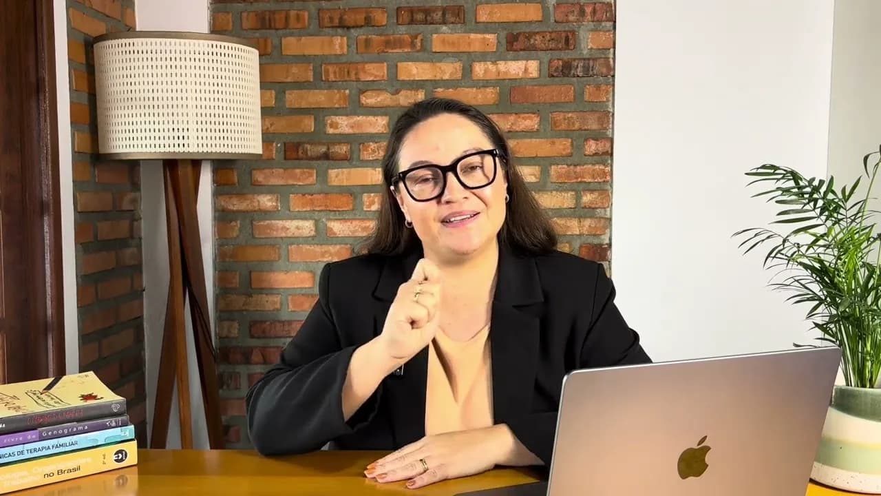 Dra. Karine Schwaab à mesma mesa, em plano mais fechado, falando com a mão erguida num gesto de explicação.