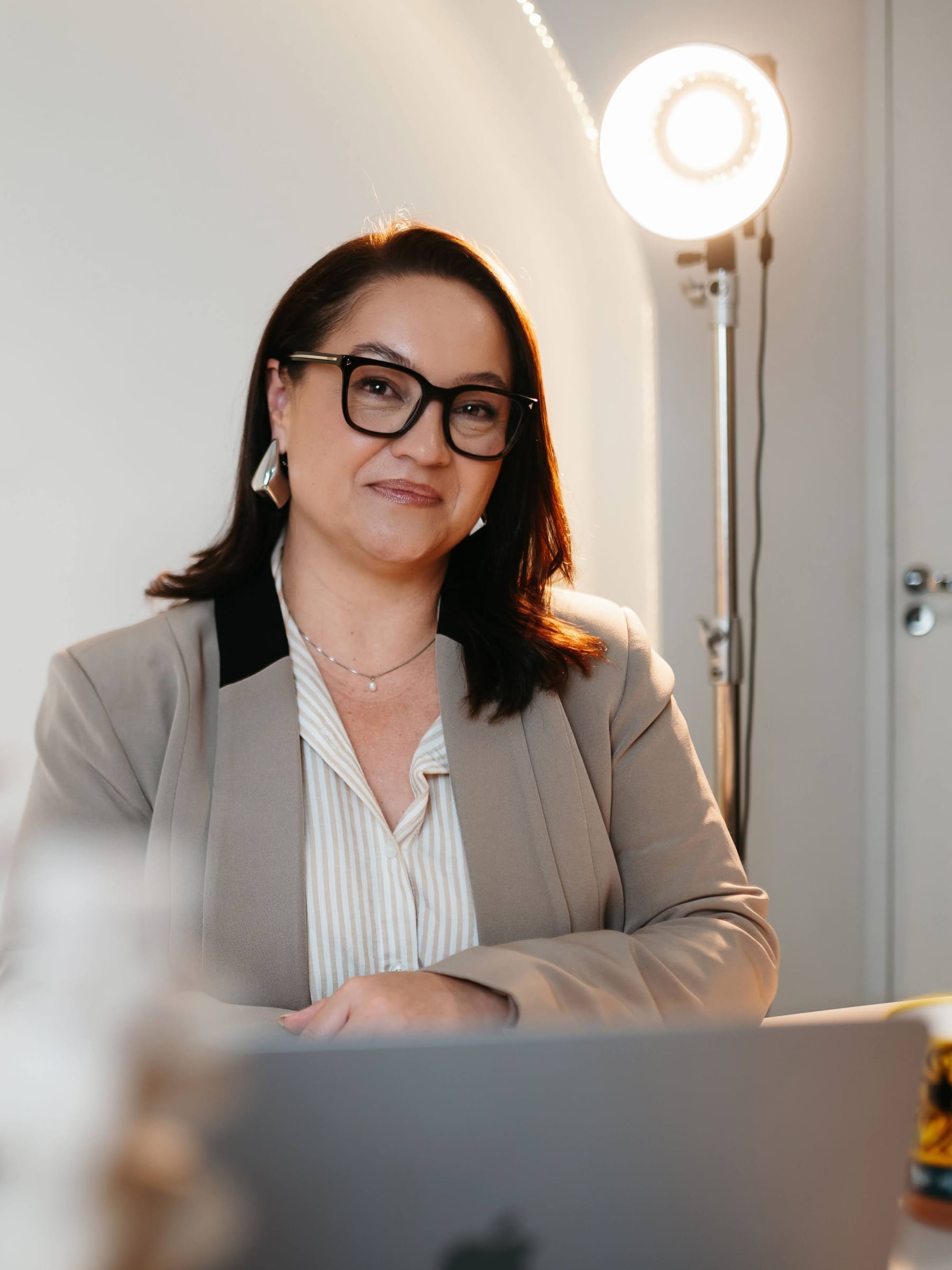 Karine trabalhando ao computador, em uma sala clara.